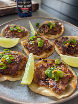 golden brown smash dumplings on a plate with wedges of lime and K-Pop Dust shaker in the background