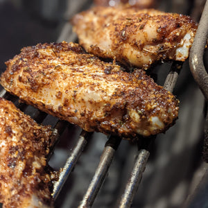 Chicken wing nibbles coated in spices on a BBQ grill