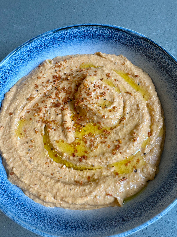 a bowl of smooth hummus drizzled with olive oil and sprinkled with hummus