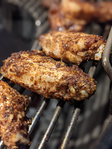 Chicken wing nibbles coated in spices on a BBQ grill