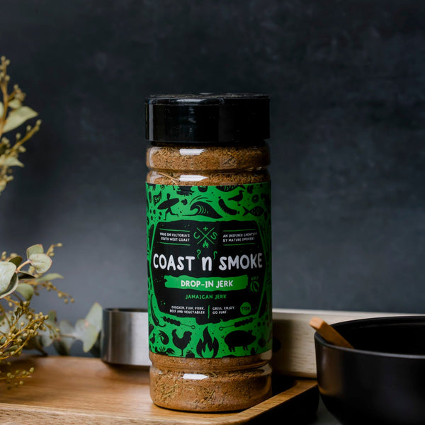 Spice blend shaker with a green label on a chopping board with a bottle opener in the foreground