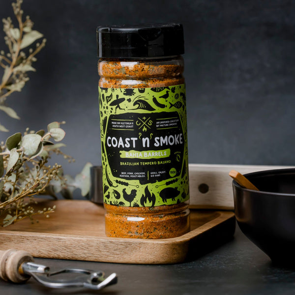 A single jar of Brazilian seasoning with decor surrounding and a grey backdrop