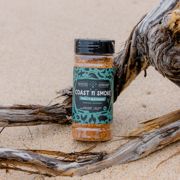 A jar of Montreal seasoning on the beach with driftwood