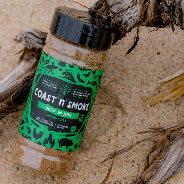 a jar of the Drop in Jerk seasoning with its bright green label sitting on the beach