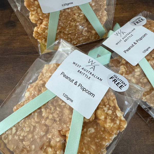 Peanut and Popcorn brittle bars in clear packaging with labels on a wooden surface