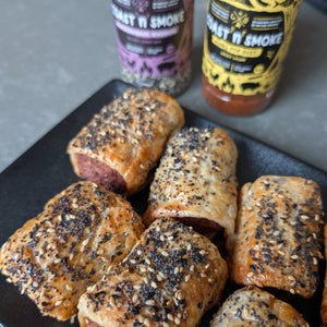 Baked sausage rolls on a black plate with 'Coast N Smoke' seasoning bottles in the background.